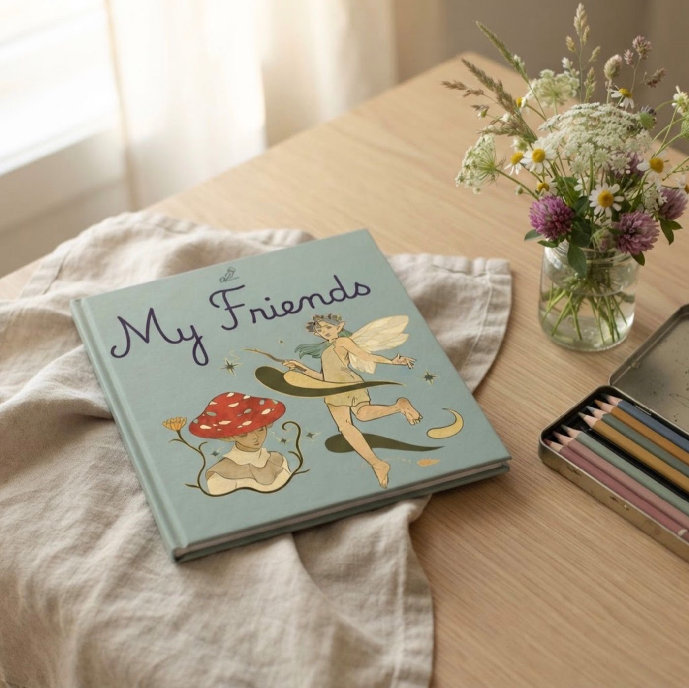 Fairies edition of My Friends Book styled with linen, wildflowers, and colored pencils